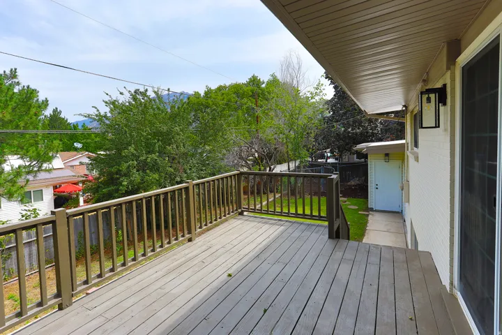 Expansive wood-finish deck with a wood railing and exterior wall sconce