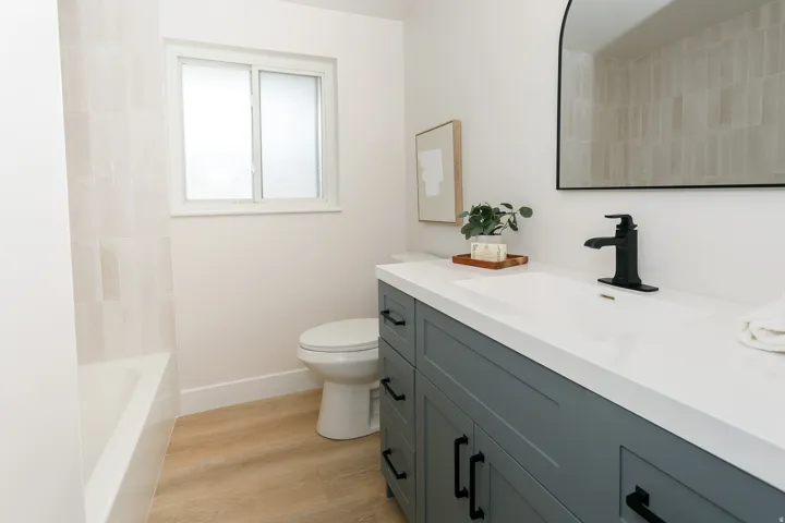 Modern bathroom with a single-sink vanity, matte black fixtures, integrated rectangular sink, and light wood-finish flooring