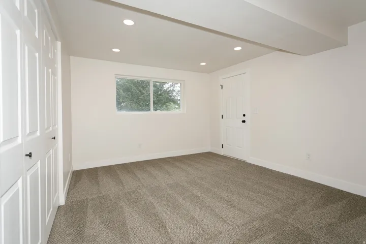 Neutral color palette throughout, recessed lighting, double-pane window, paneled interior door, and panel closet doors