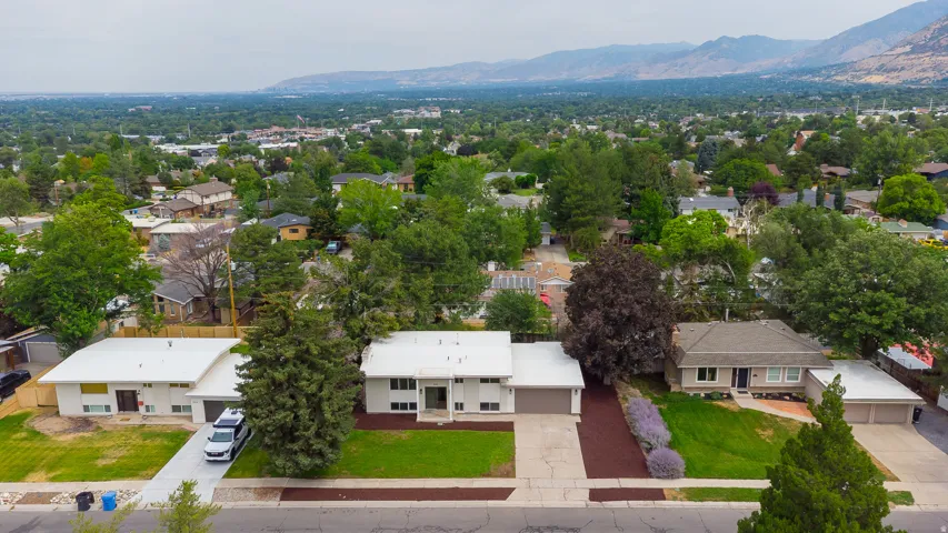 Mid-century modern exterior featuring a flat roofline, integrated garage, and expansive front lawn