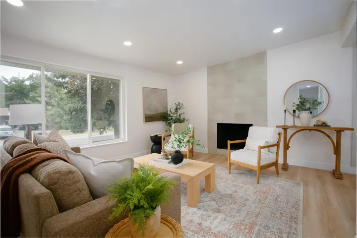 Recessed lighting, light wood-finish flooring, a contemporary fireplace with a light-colored tiled surround, and large windows