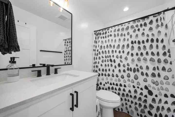 White vanity with dark hardware, undermount sink, and light-colored countertop
