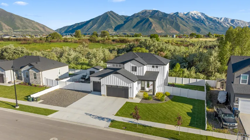 Modern farmhouse-style residence featuring a white exterior with black accents, a two-car garage, and a fenced backyard