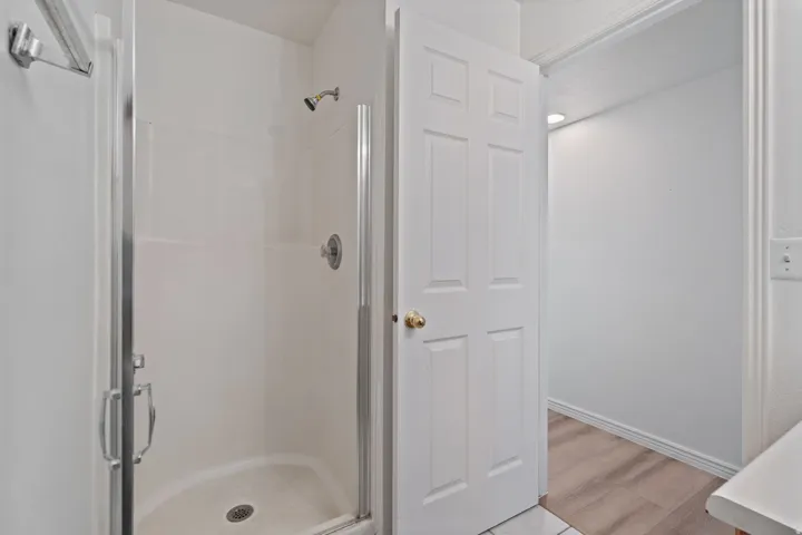 Shower enclosure with a glass door, wall-mounted showerhead, and chrome fixtures