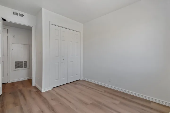 Wood-finish flooring throughout, white walls, and a bi-fold closet with panel doors