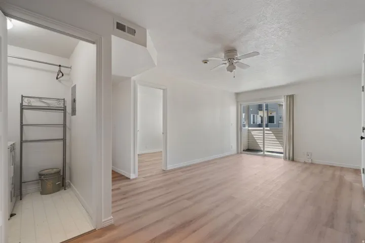 Wood-finish flooring, ceiling fan with integrated lighting, sliding glass door, and a dedicated laundry alcove
