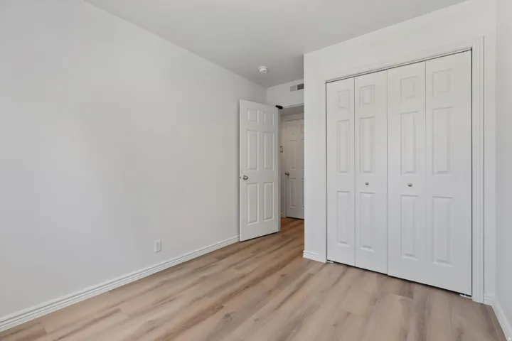Wood-finish flooring with crisp white walls and bi-fold closet doors