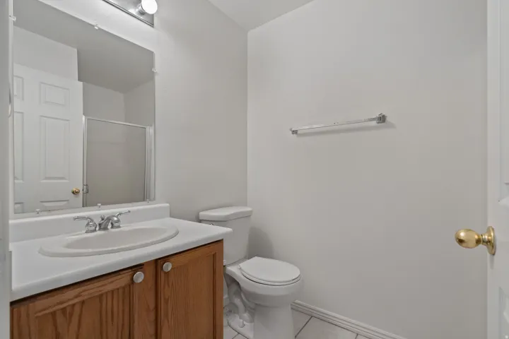 Vanity with wood-finish cabinetry, integrated sink, and chrome-finish faucet