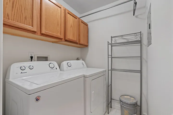 White laundry appliances with overhead wood-finish cabinetry