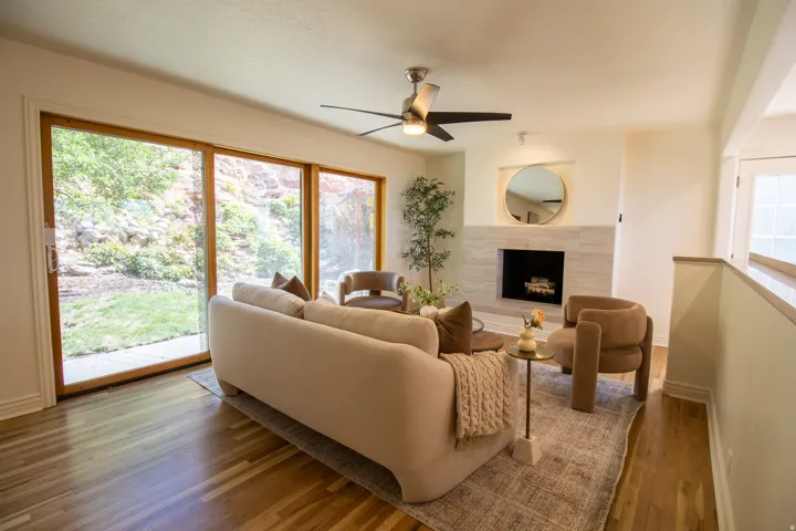 Spacious living area featuring hardwood flooring, a contemporary ceiling fan, and large sliding glass doors