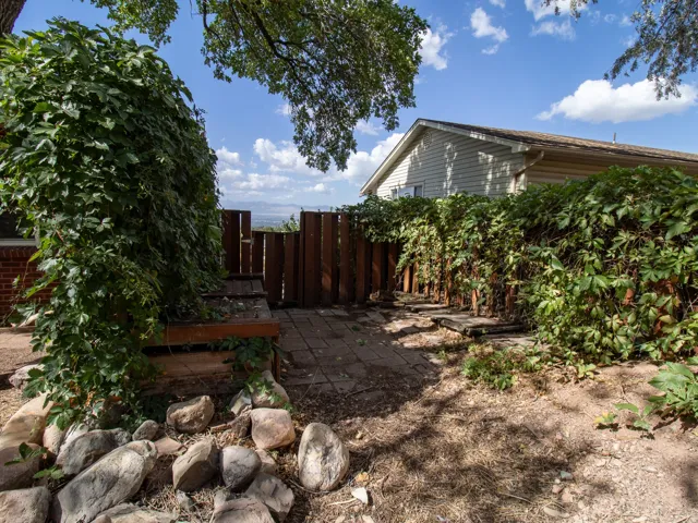 Brick exterior, wood privacy fence, stone retaining wall, mature trees, and a ground-level patio