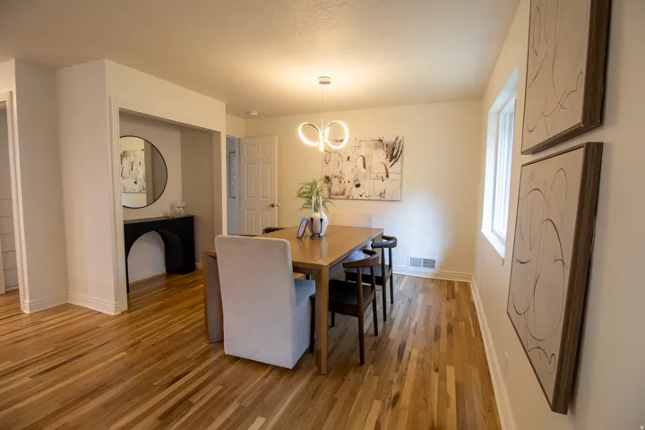 Hardwood flooring, recessed lighting, modern pendant light fixture, white trim, and a built-in archway