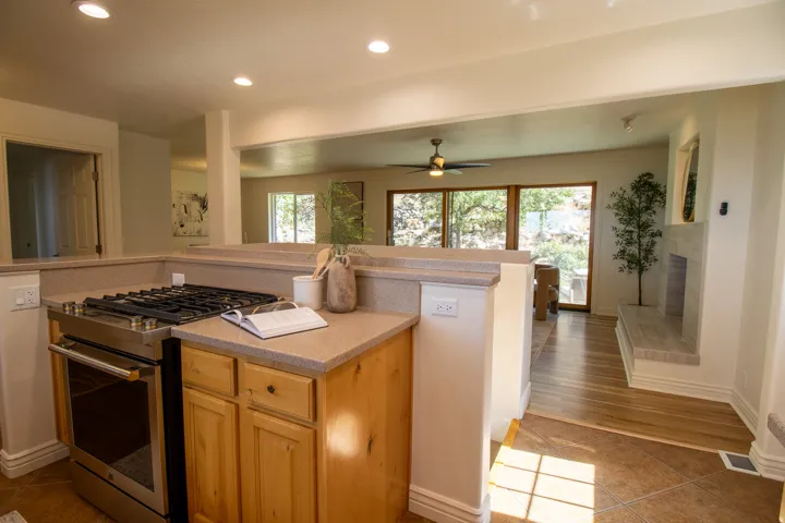 Stainless steel range with gas cooktop, natural wood cabinetry, recessed lighting, and a Corian countertop
