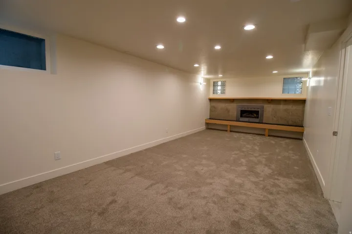 Carpeted room featuring a built-in fireplace with tile surround, recessed lighting, and a long wood bench