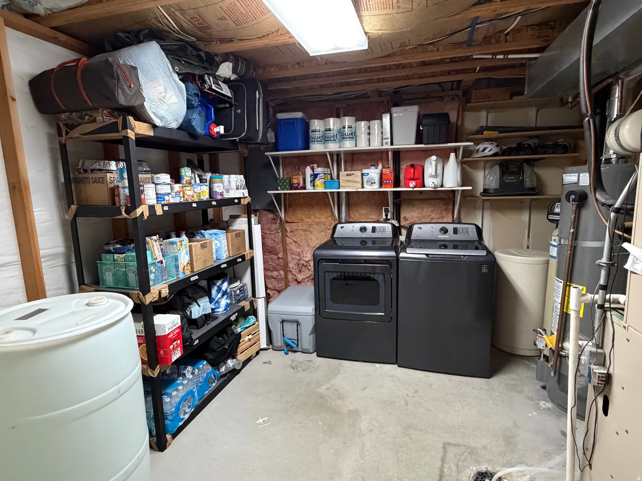 Laundry area featuring a washer and dryer, concrete flooring, and exposed ceiling joists