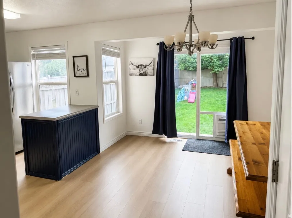 Light wood-finish flooring throughout, with a dark blue kitchen island featuring a light-toned countertop