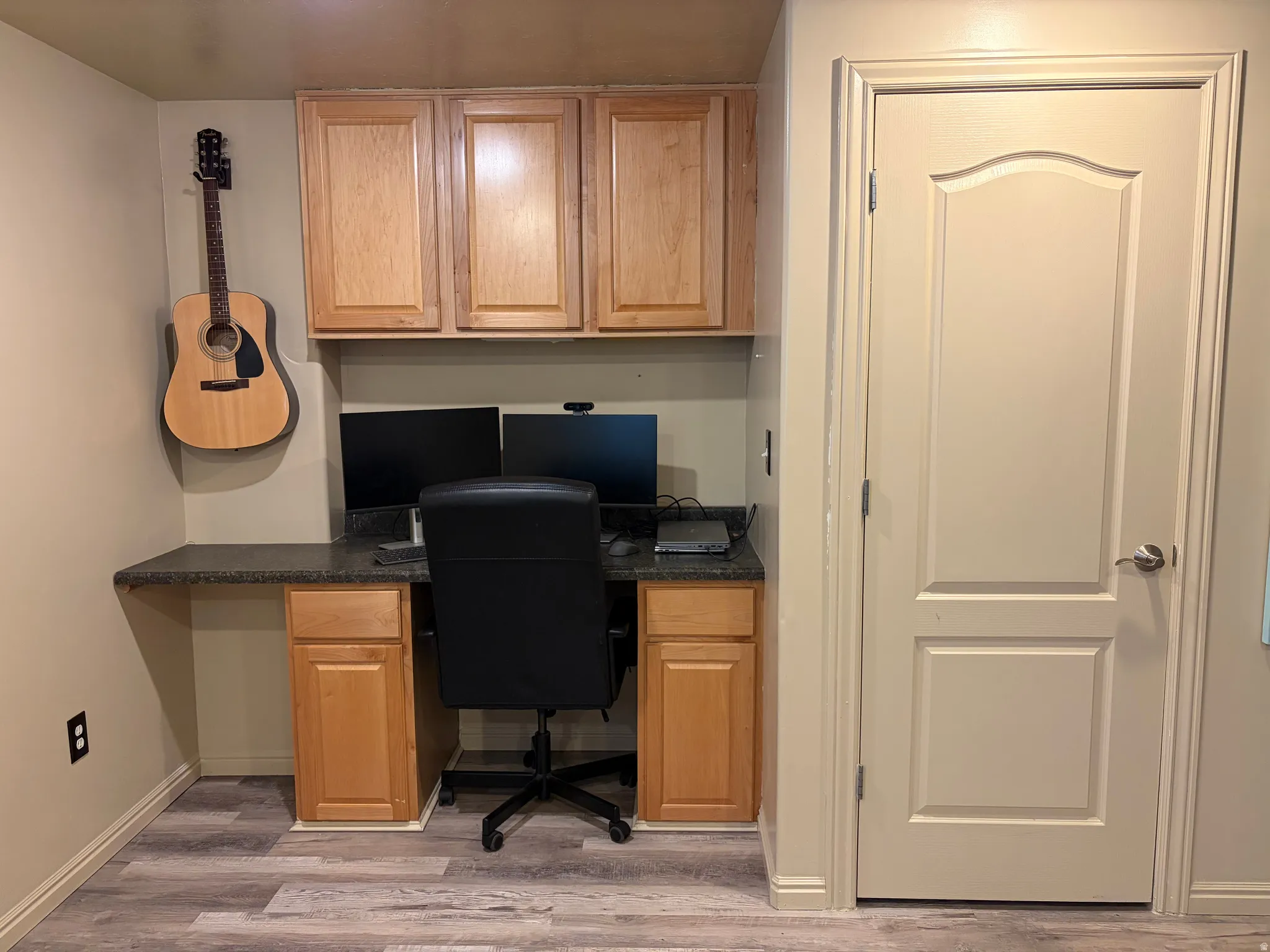Built-in desk with a dark countertop and ample cabinet storage