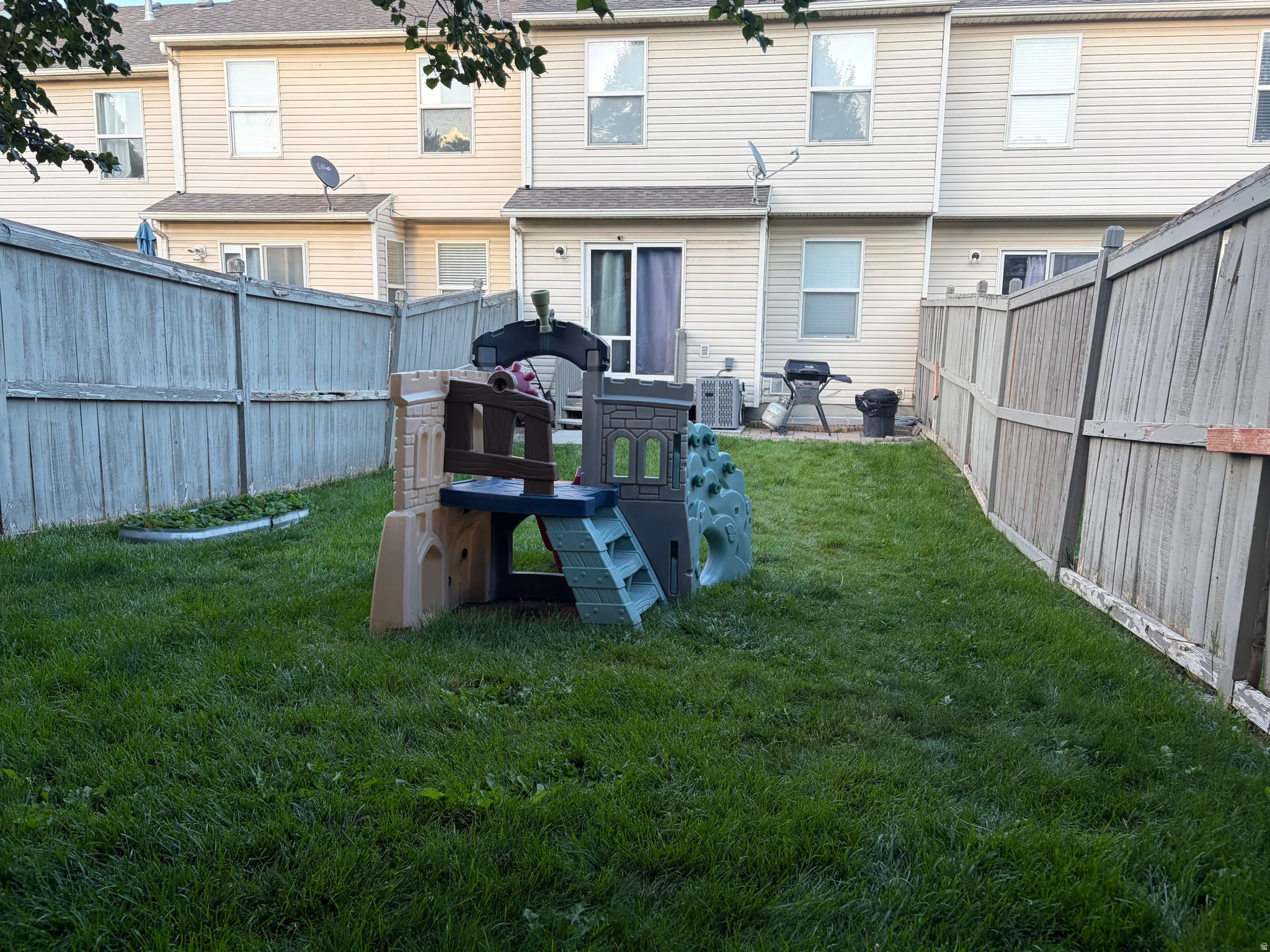 Fenced backyard featuring a grassy lawn, sliding patio door, and vinyl siding exterior