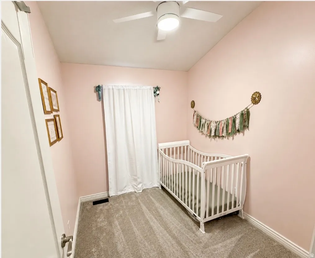 Vaulted ceiling, ceiling fan with integrated lighting, wall-to-wall carpeting, and a window with white drapery