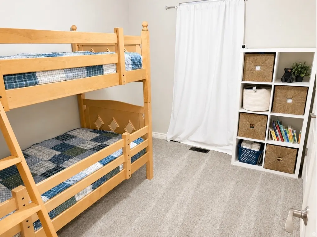 Plush carpet flooring, light neutral wall paint, and a built-in modular storage unit with cubbies