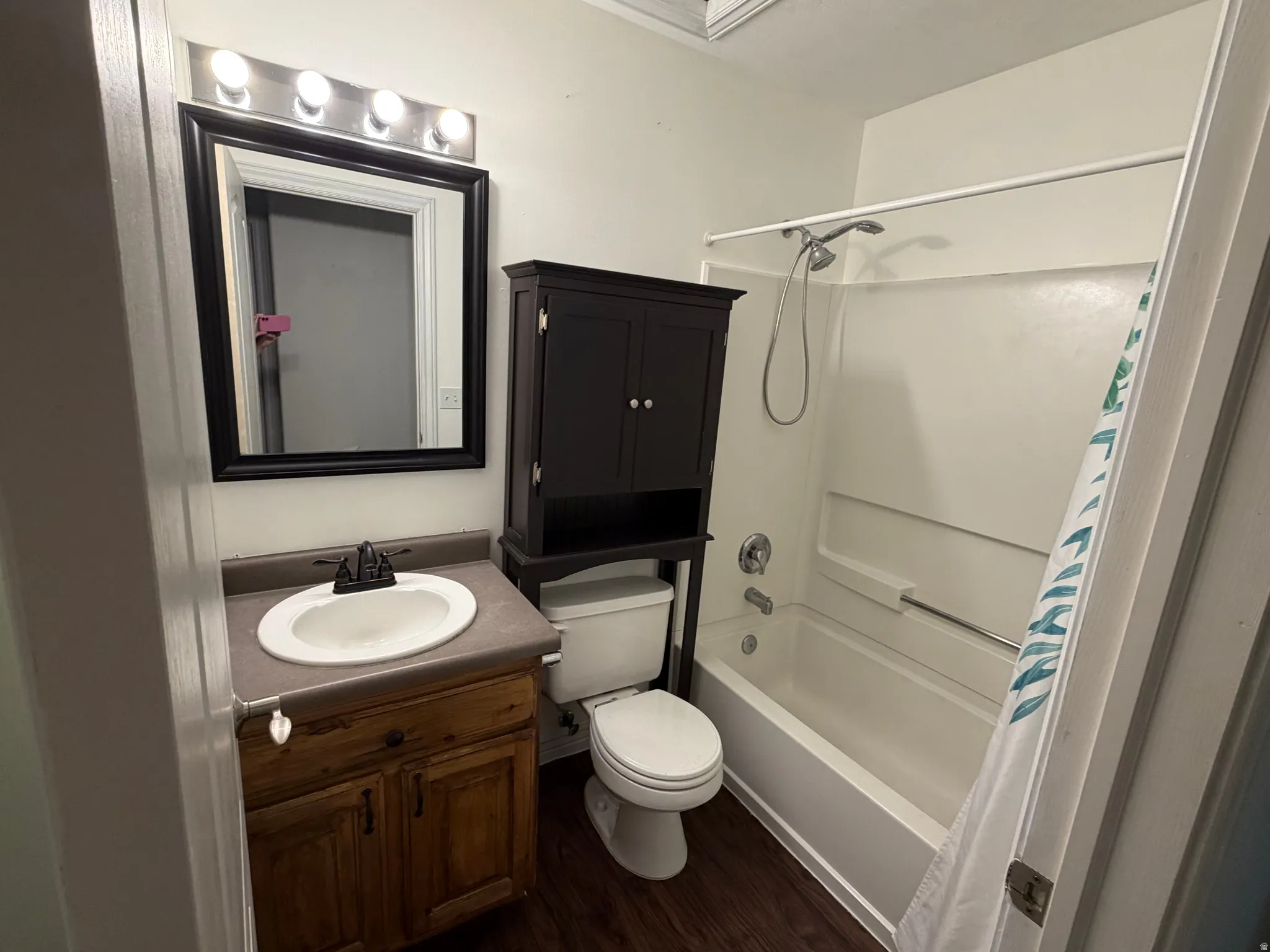Vanity with wood-finish cabinetry, a drop-in sink, and a dark countertop