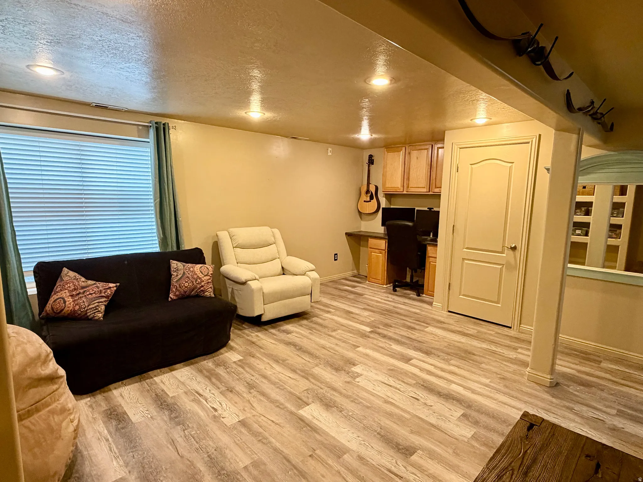 Recessed lighting, wood-finish flooring, built-in desk, upper cabinetry, and a window with blinds