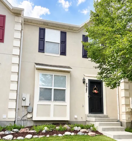 Stucco exterior with decorative shutters, bay window feature, and concrete entry steps