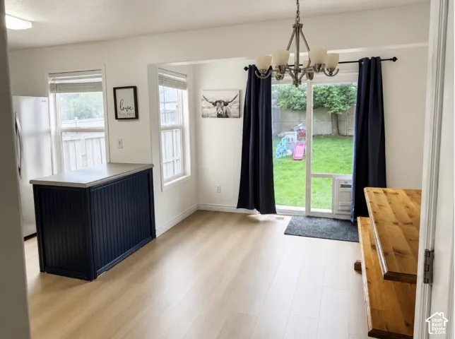 Light wood-finish flooring throughout, with a dark blue kitchen island featuring a light-toned countertop