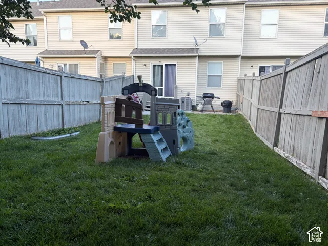 Fenced backyard featuring a grassy lawn, sliding patio door, and vinyl siding exterior