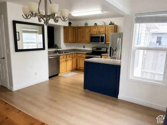 Kitchen featuring wood-finish cabinetry, stainless steel appliances, a center island with a beadboard base, and wood-finish flooring