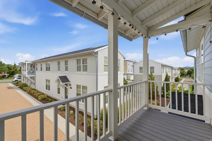 Covered balcony with composite decking, white railing, and exposed beam ceiling
