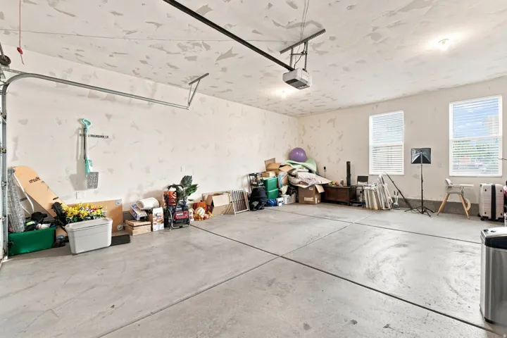 Spacious garage with two windows, concrete flooring, and an automatic garage door opener