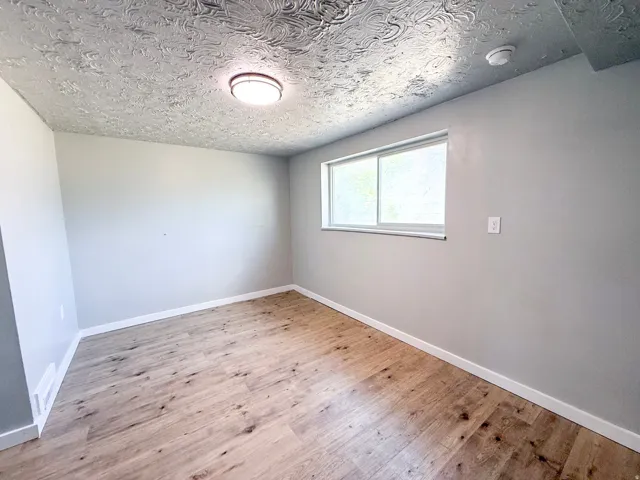 Wood-finish flooring, white baseboards, and light gray wall paint