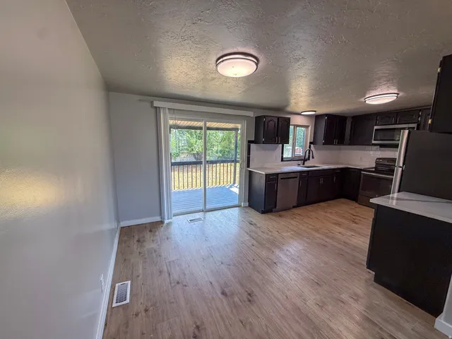 Kitchen featuring wood-finish flooring, dark cabinetry, light countertops, and stainless steel appliances