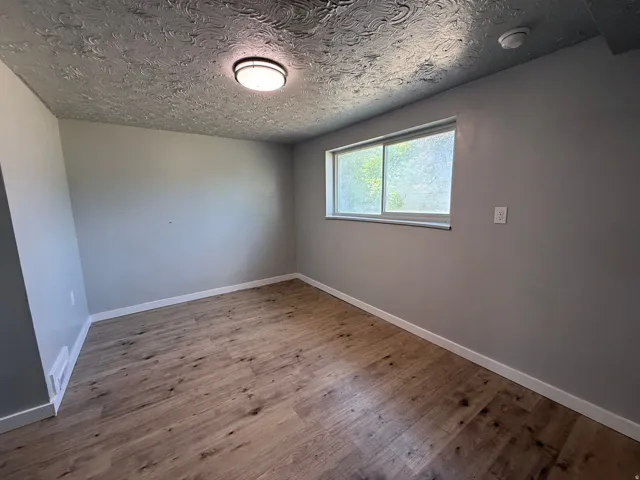 Wood-finish flooring, recessed window, overhead flush-mount lighting, smooth wall finishes, and white trim