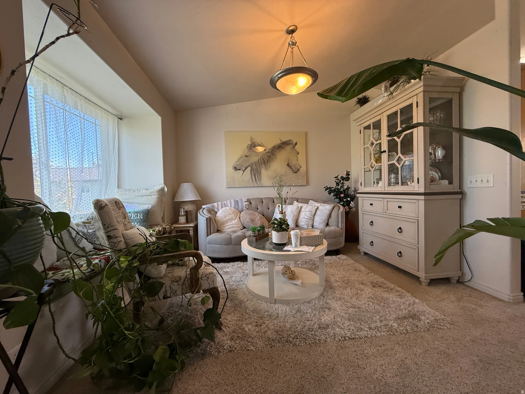 Recessed window alcove, vaulted ceiling, built-in display cabinetry, hanging ceiling light fixture, carpeted flooring