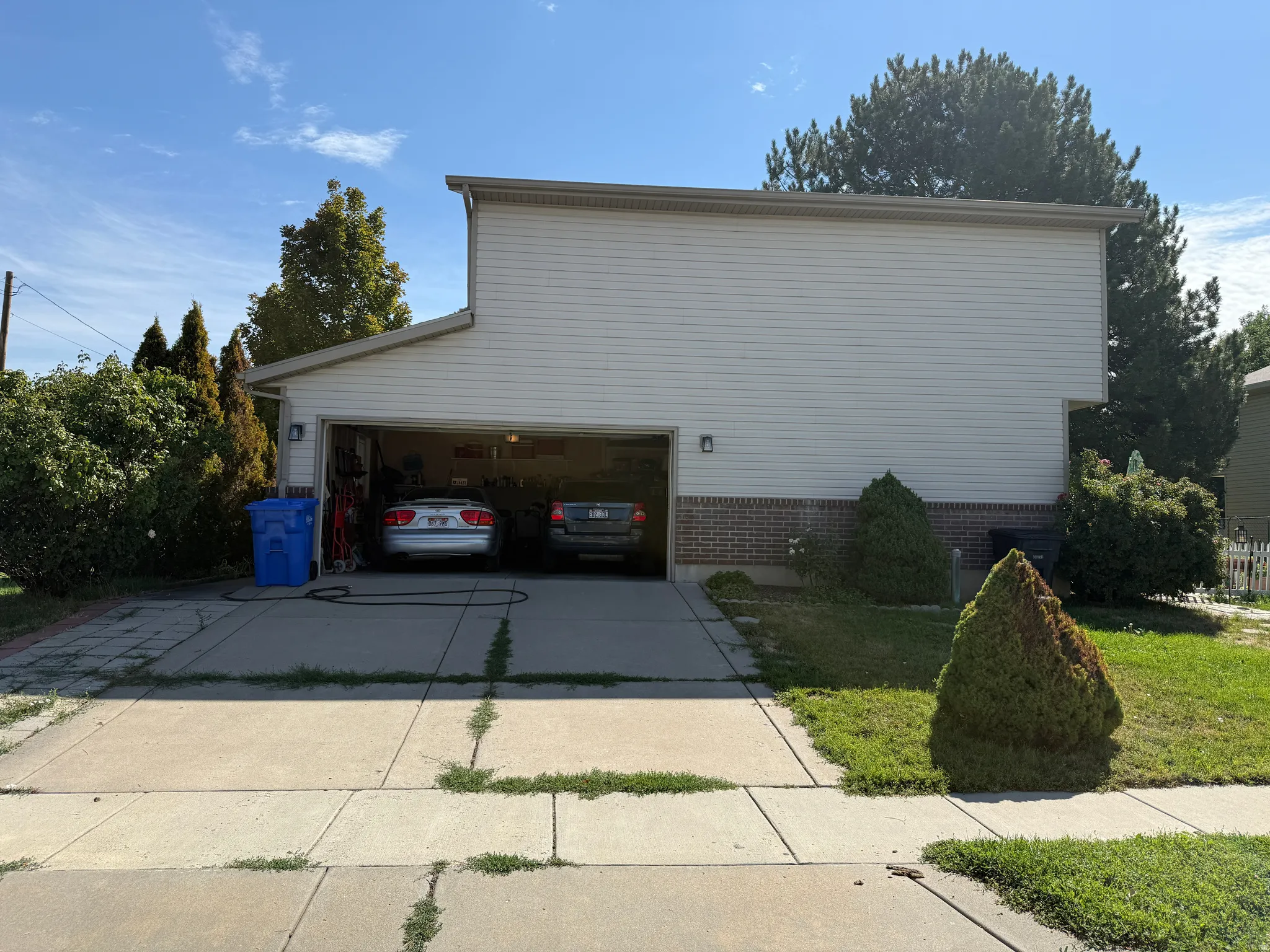 Two-car garage with overhead door, vinyl siding, and brick veneer foundation