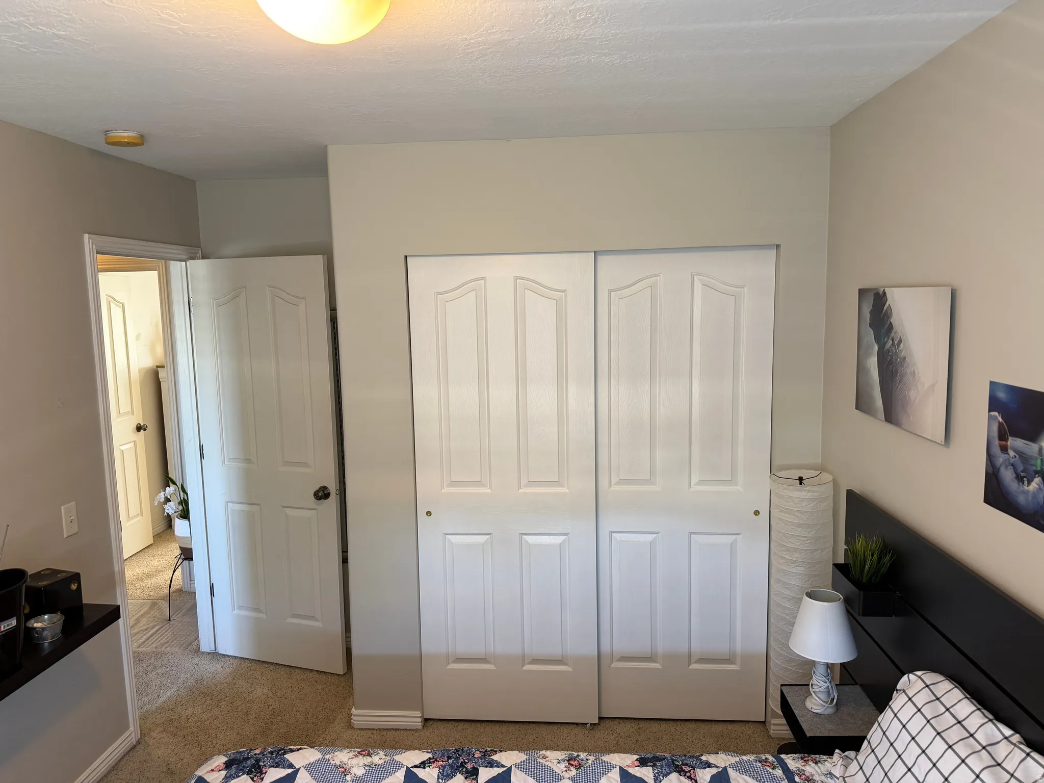 Bedroom #1 other view. Interior space featuring neutral wall tones, white bi-fold closet doors, and carpet flooring