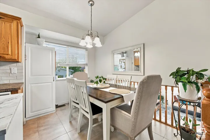 Dining area featuring a vaulted ceiling, tile flooring, and a chandelier