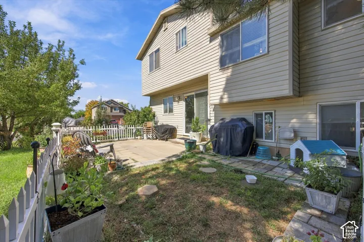 Expansive rear patio with concrete and paver sections, perimeter fencing, and established landscaping