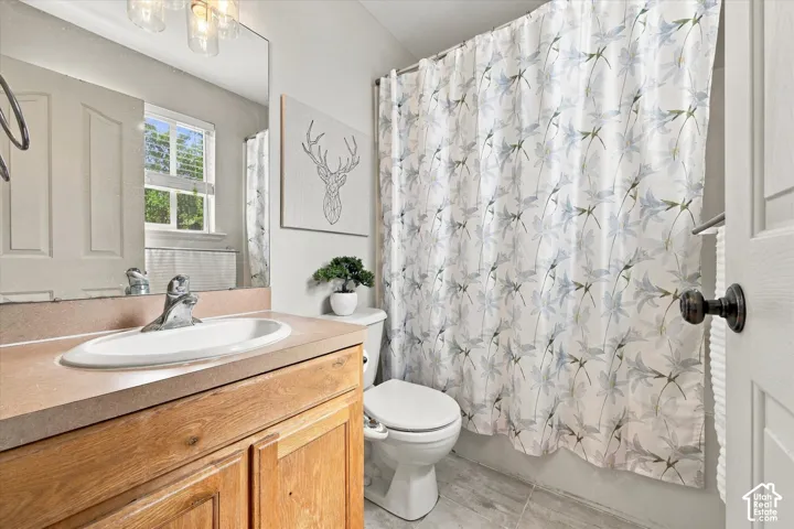 Bathroom featuring a wood-finish vanity with an integrated sink, a built-in mirror, and a window with blinds