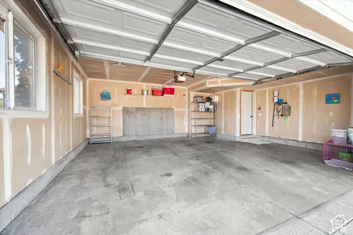 Concrete flooring with drywall walls, two windows, and an interior access door