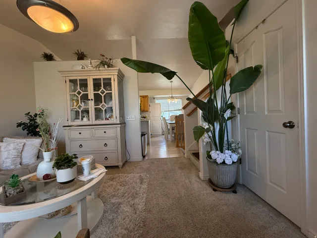 Other view of the Living room. Vaulted ceilings with an overhead light fixture, carpeted flooring, and a white paneled door
