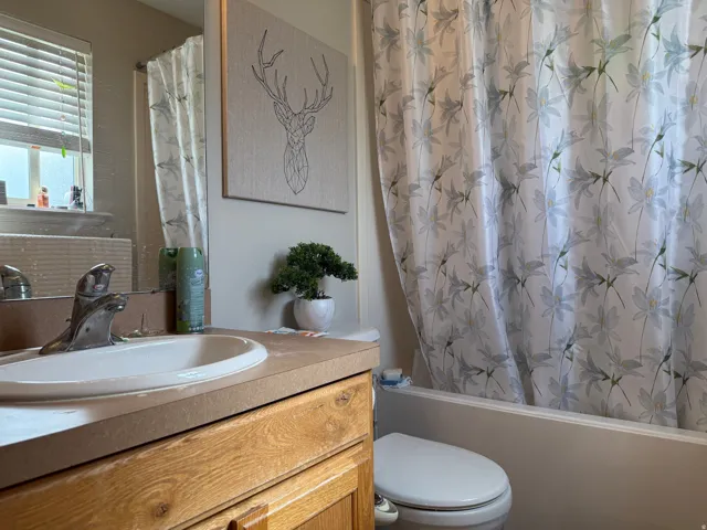 Bathroom #2. Built-in vanity with wood-finish cabinetry, integrated sink, and an expansive wall mirror
