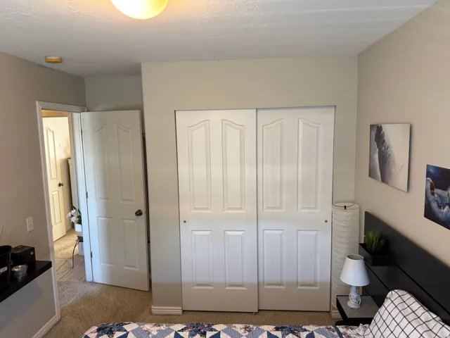 Bedroom #1 other view. Interior space featuring neutral wall tones, white bi-fold closet doors, and carpet flooring