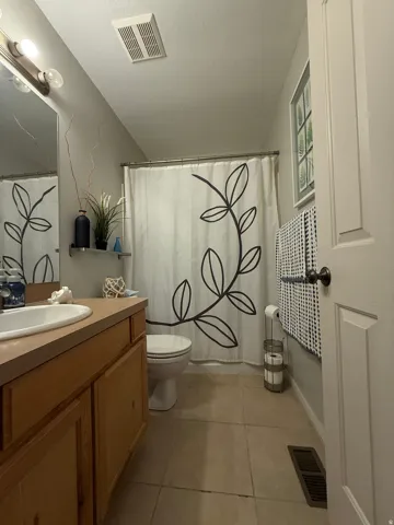 Master Bathroom. Wood-finish vanity with an integrated sink, tiled flooring, and a shower/tub combination
