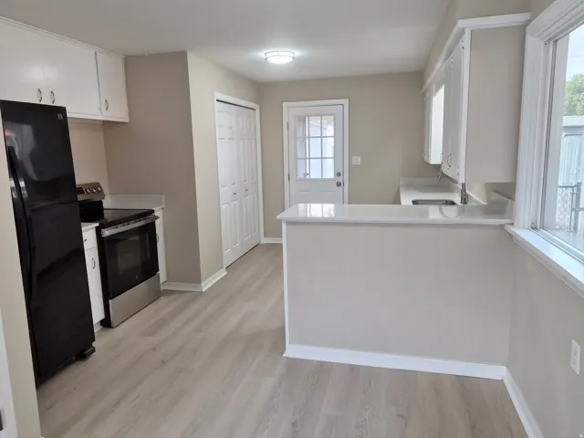 Kitchen featuring white cabinetry, light-toned flooring, white countertops, and a full suite of appliances