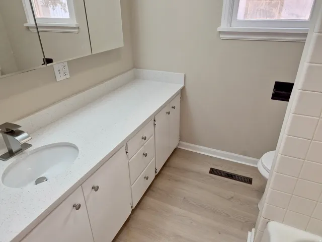 Elongated white vanity with an integrated sink, brushed nickel faucet, and a wall-mounted medicine cabinet