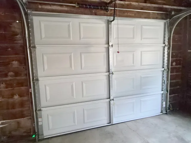 Panel-style garage door with automatic opener hardware and concrete flooring