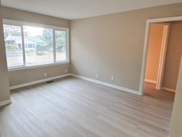 Light-toned wood-finish flooring, neutral wall paint, and white trim